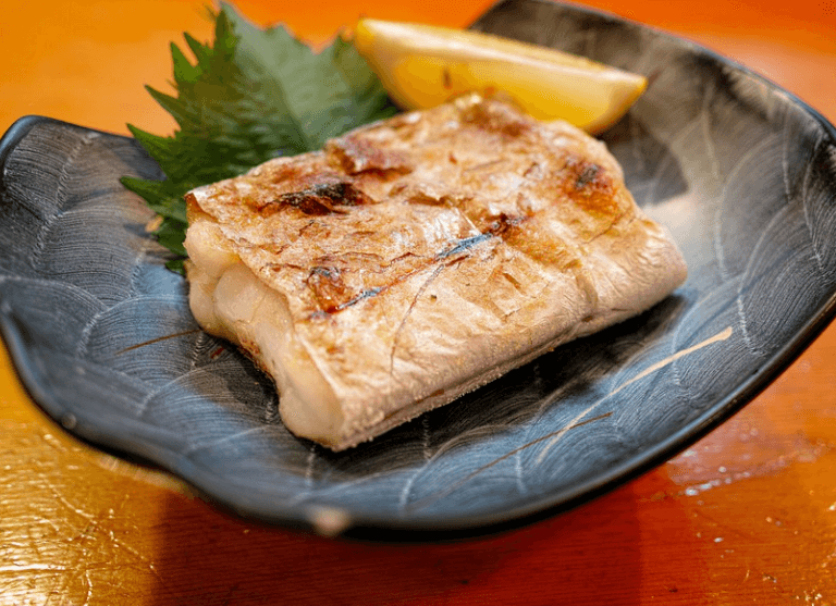 구운 갈치가 검은 접시에 담겨 있다