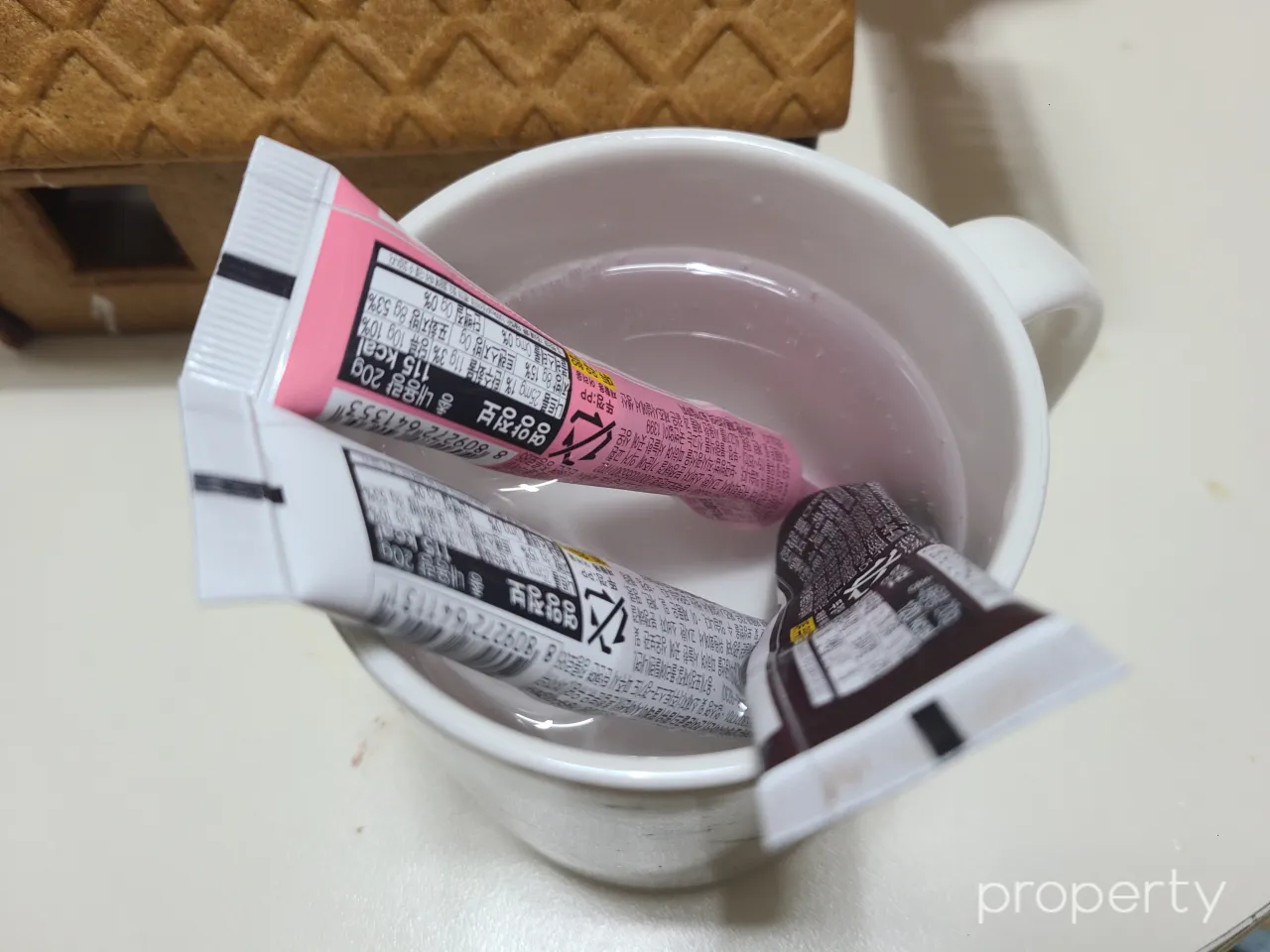 하얀색머그컵-따뜻한물속-분홍색흰색갈색초코펜3개를담궈놓은모습