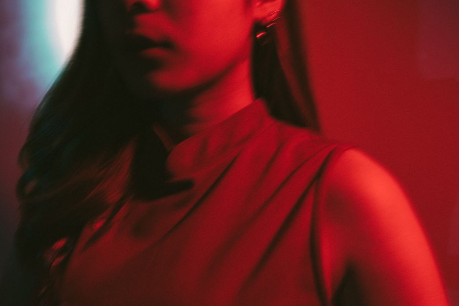 Artistic portrait of a woman in dramatic red lighting creating a mysterious mood.