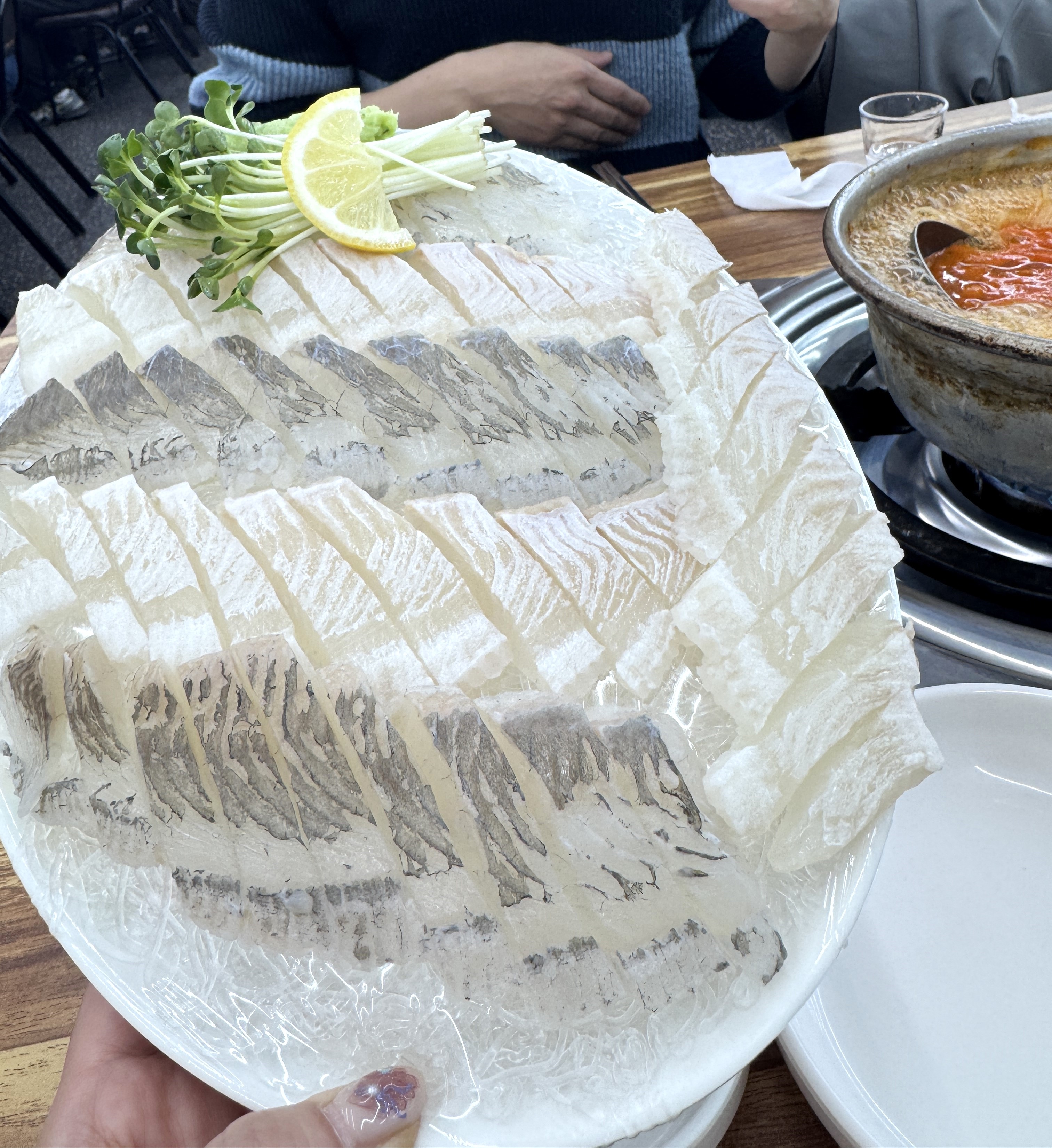 얇게 썰린 도다리회가 접시에 가득 담기고 옆에 알탕이 놓인 테이블 구성 사진