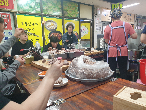 서서 기다리는 손님과 이제 막 앉은 손님 그리고 맛있게 먹고 있는 손님