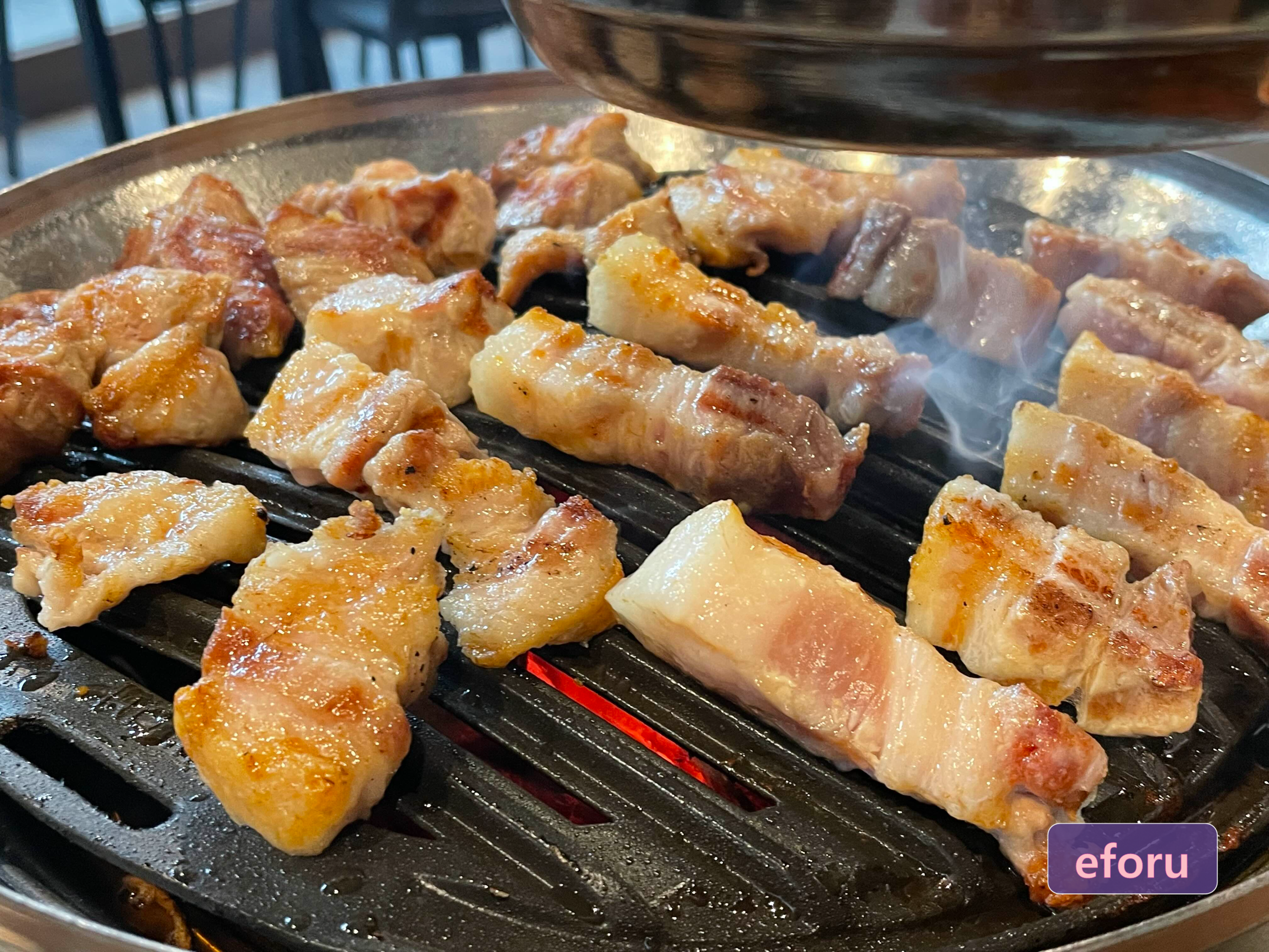 불판 위에서 고기가 익고 있고 연기가 생기는 모습입니다.