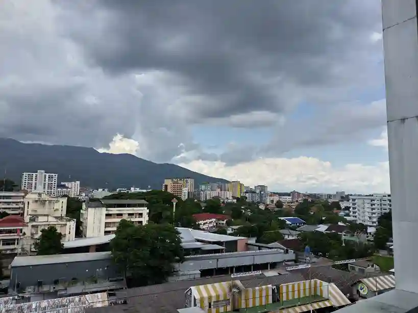 태국 치앙마이 싼티탐, 님만해민 지역의 구름 낀 하늘과 주변 건물 및 산이 보이는 전경