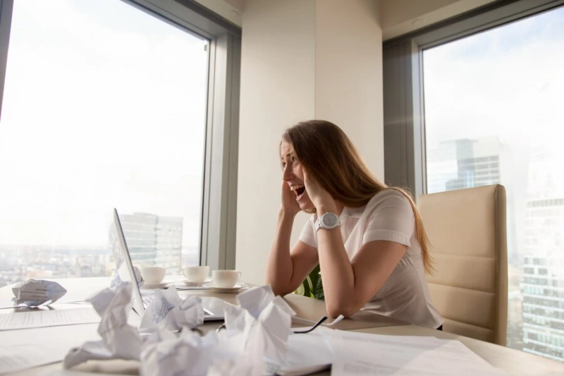 스트레스로 책상에 앉아 머리를 두손에 대고 괴로워 하는 여성