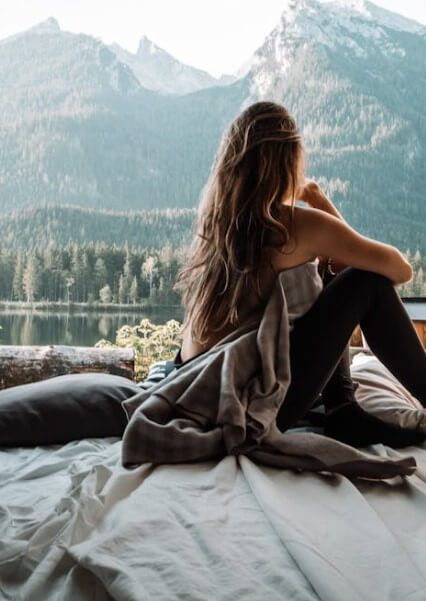 자연 풍경을 바라보며 침대에 앉아 있는 여성의 모습으로, 내면의 고요함과 감정 회복의 순간을 시각적으로 표현합니다.