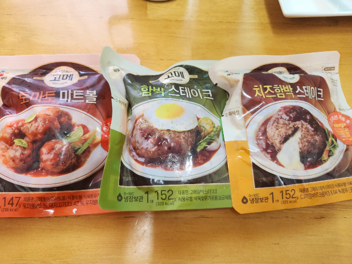 CJ 고메 토마토 미트볼, 함박 스테이크, 치즈함박 스테이크가 테이블 위에 올려져 있다