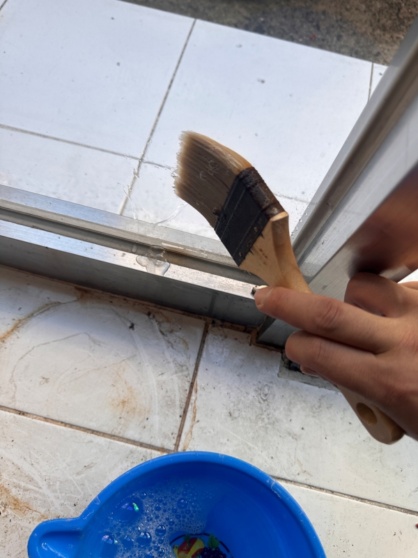 붓을 이용하여 유리창에 바르고 있습니다.