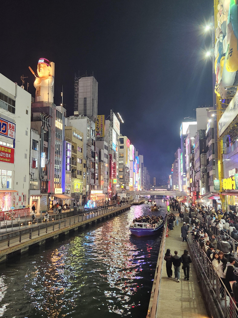 어두운 밤 중앙에 강이 흐르고 양쪽에는 불빛 가득한 건물들이 보인다.