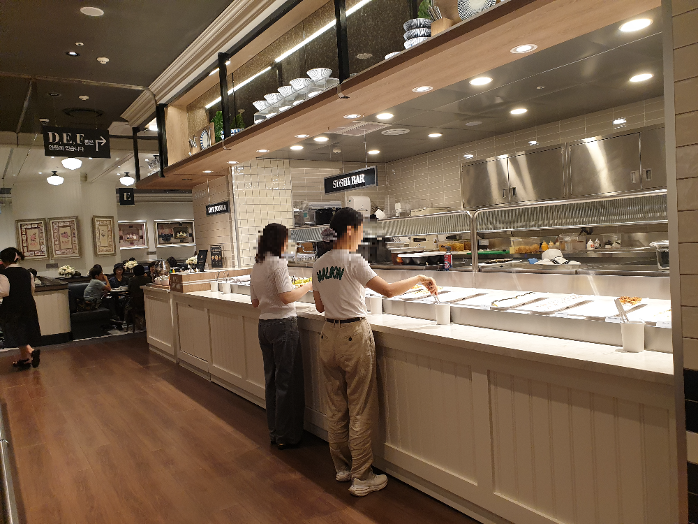 스시코너에서 사람들이 스시를 담고 있다.