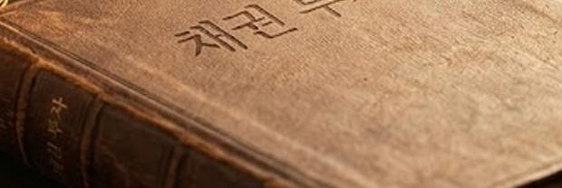 채권 투자와 금리 흐름을 분석하는 그래프를 들고 있는 모습과 모래시계&amp;#44; 동전 더미&amp;#44; 채권 투자 책이 함께 놓인 재테크 이미지
