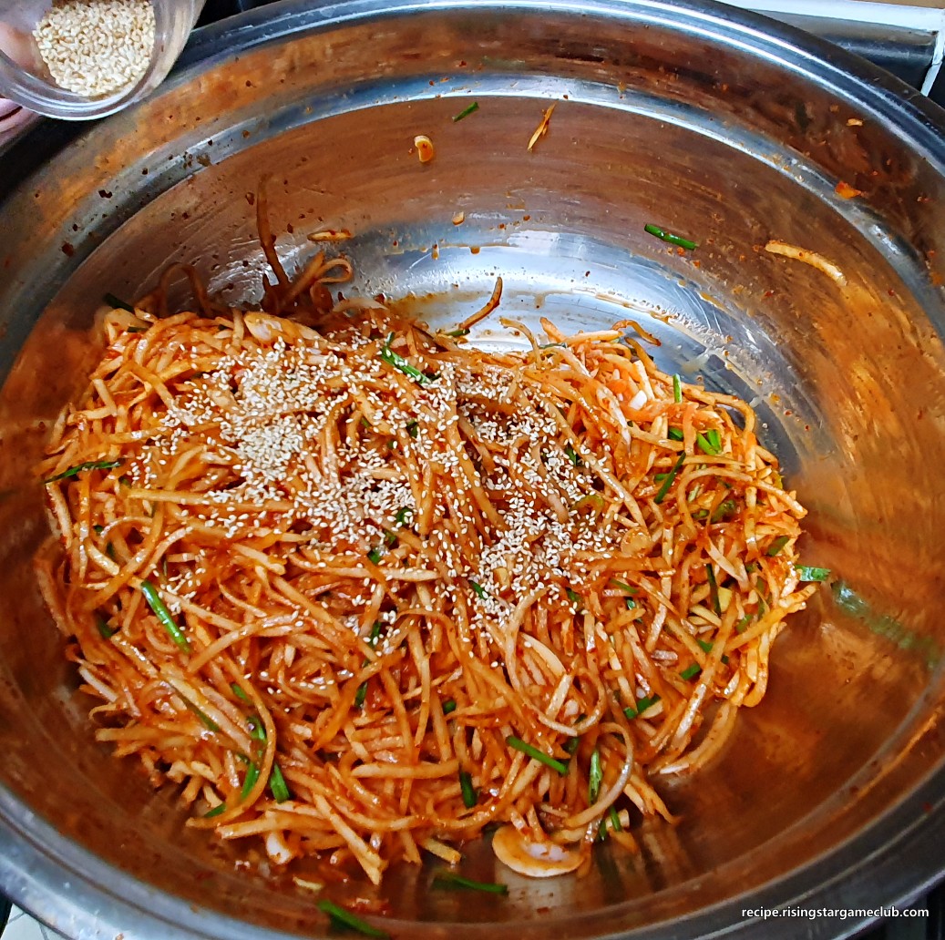 무생채 무침에 통깨를 솔솔 뿌려주는 사진