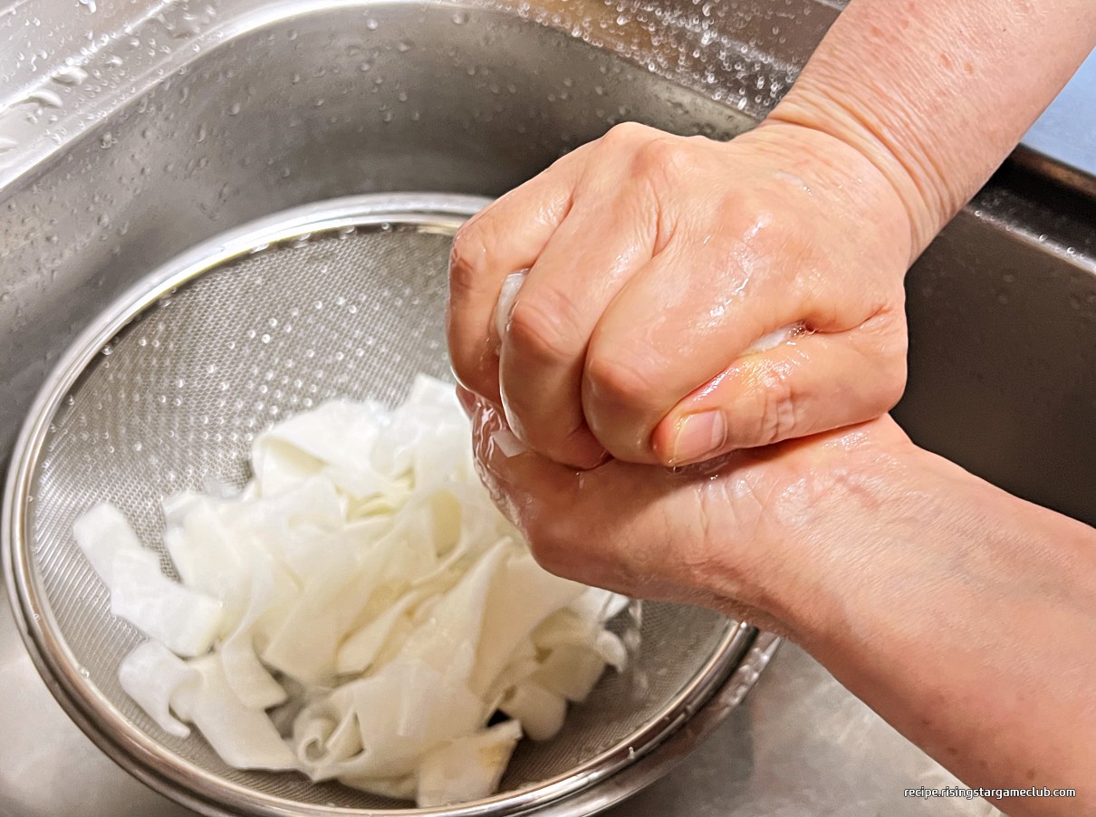 냉면 고명용 절인 무의 물기를 제거하기 위해서 두손으로 꼭 짜고 있는 사진