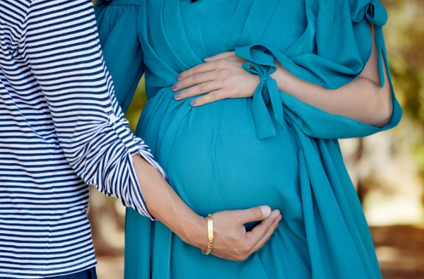 임신한 여성의 배를 보호하며 손을 얹고 있는 부부의 모습, 태아 건강과 임신 중 생활습관의 중요성을 상징
