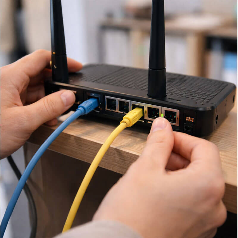 랜 케이블과 공유기 연결 상태를 확인하며 인터넷 장비를 점검하는 실내 장면