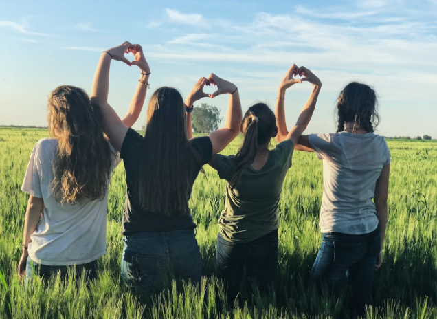 네명의 여자 친구들이 손을 올려 함께 하트를 만들고 있는 사진