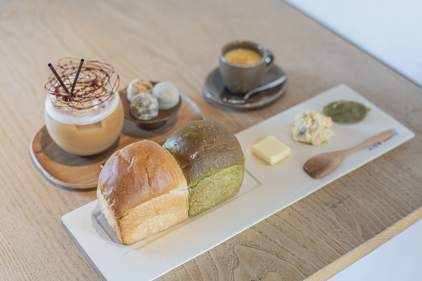 Kyoto Gion Saryo: small white and green loaves, accompaniments and drinks, one topped with cream, fill the table.