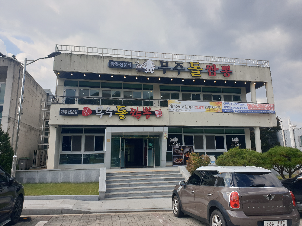 2층 건물에 무주돌짬뽕 간판이 있다. 건물 앞에는 주차된 차량이 하나 보인다.