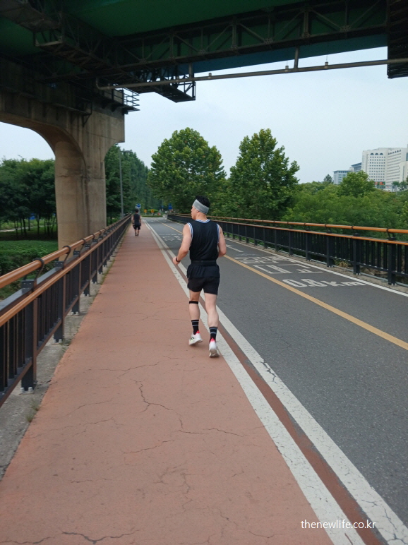 다리 아래 자전거 도로에서 조깅하는 사람 – 장시간 운동으로 체내 소금 부족 증상을 유발할 수 있는 장면