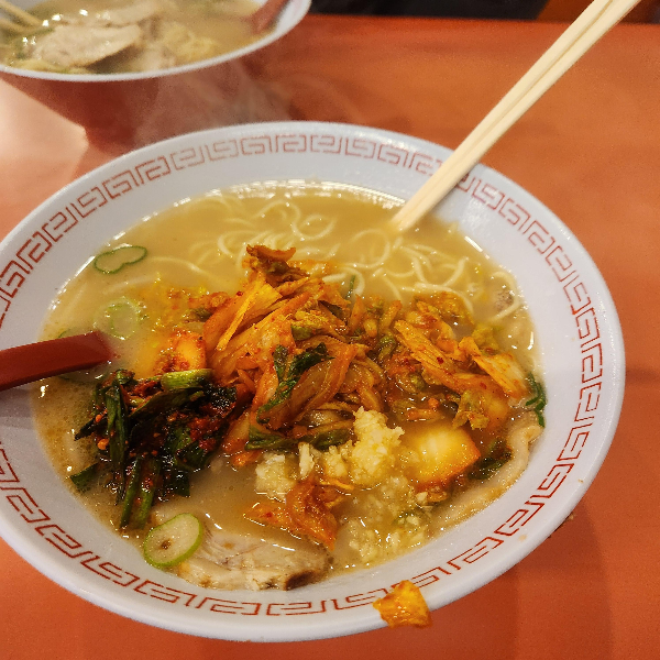 라멘 위에 김치 마늘 부추가 올려져 있다.