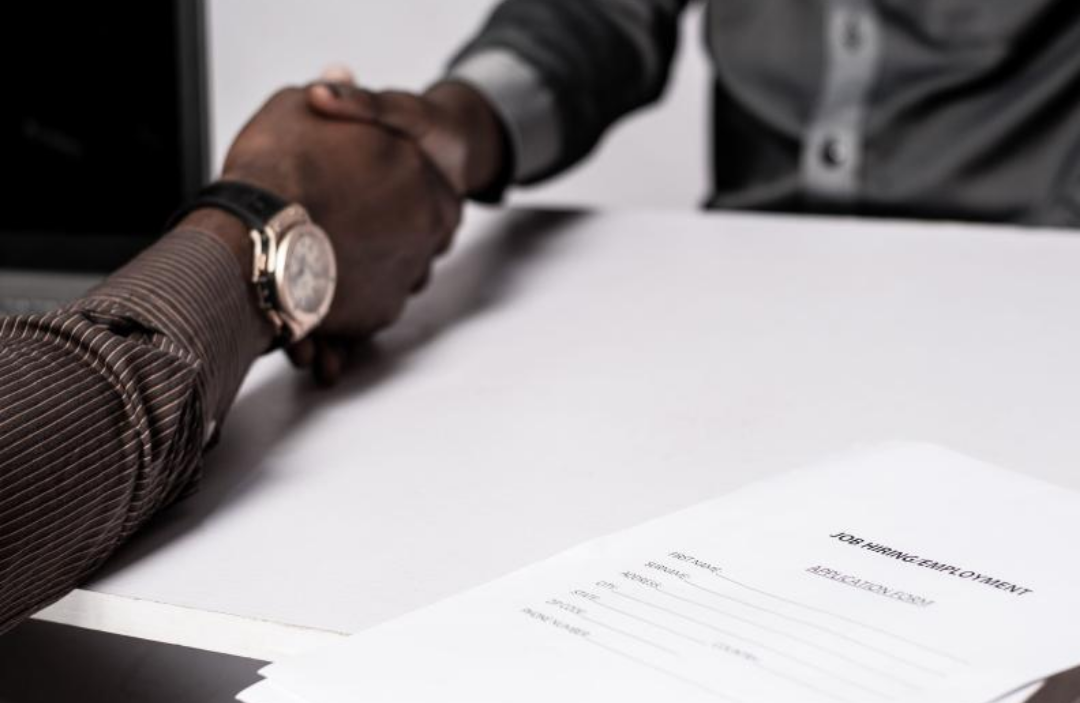 서류를 두고 두 남자가 악수를 하고 있다.