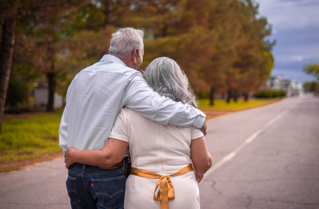 노부부가 서로를 껴안은 채 걷고 있다.