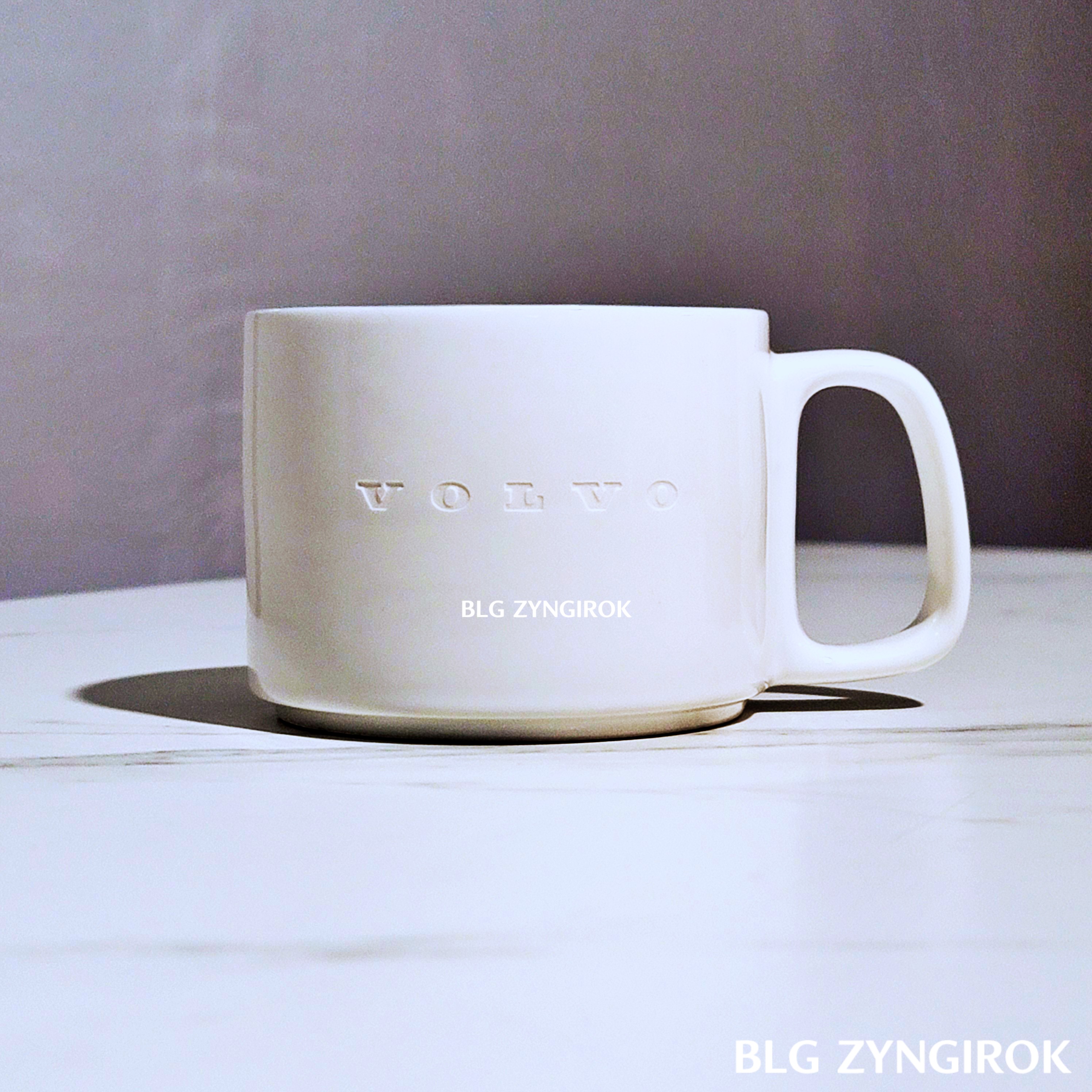 볼보 흰색 머그컵이 테이블 위에 놓여있다.