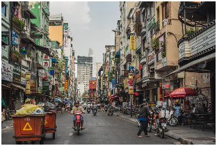베트남 도시 스카이라인과 오토바이 행렬을 바라보는 이주자 실루엣
