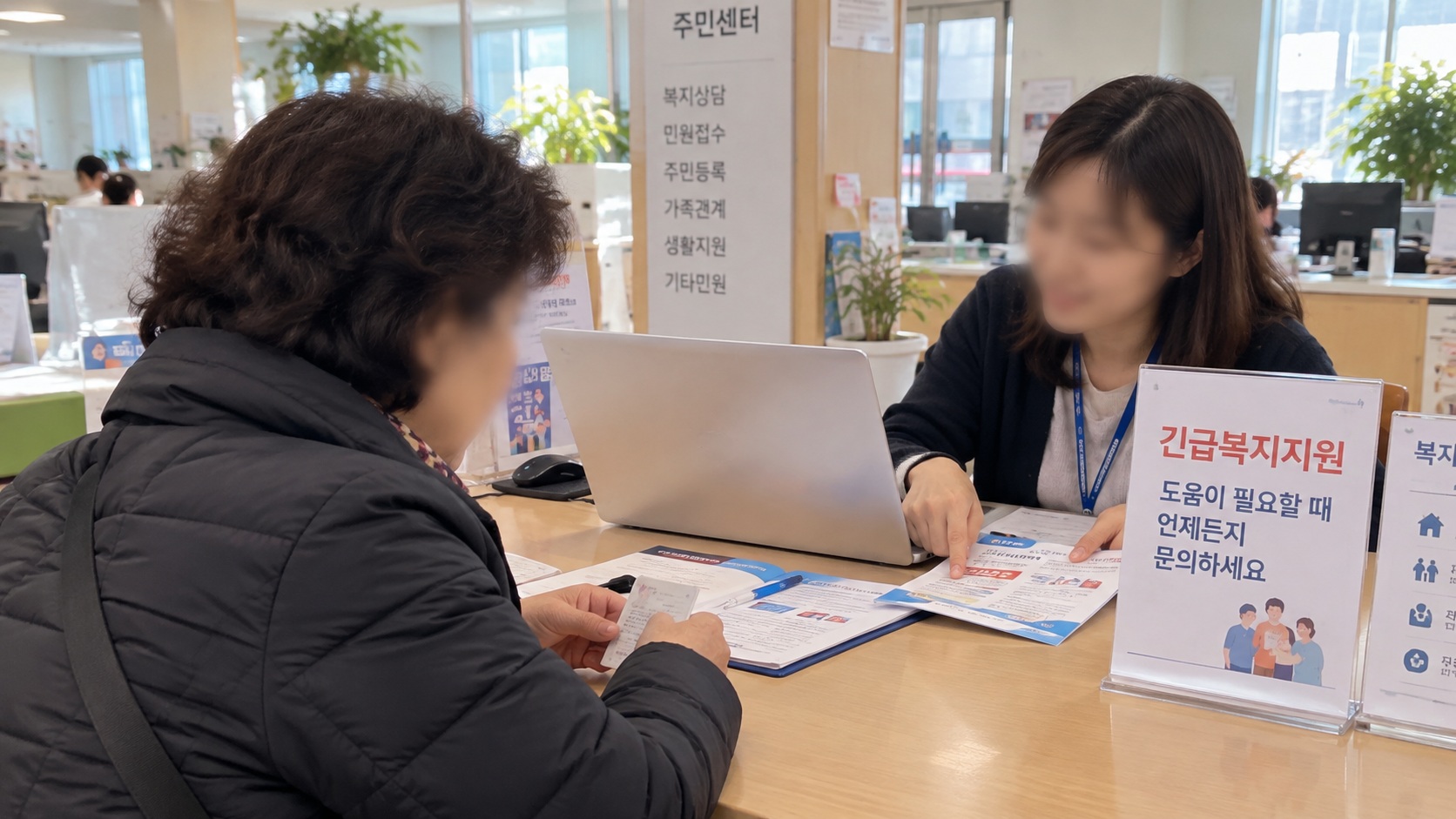 주민센터 복지상담 창구에서 신분증을 준비한 주민이 긴급복지 생계지원금 신청방법을 안내받는 모습