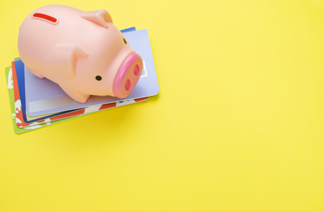 통장들이 쌓여있고 그 위에 돼지저금통이 있다.