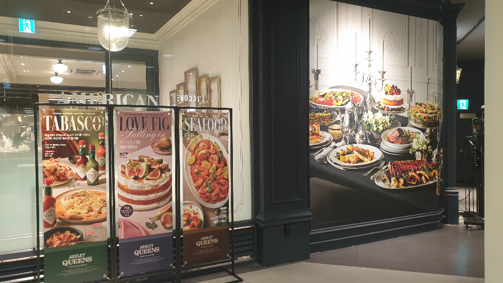 외부에 3개의 베너가 보인다. 큰 기둥에는 음식 사진이 들어있다.