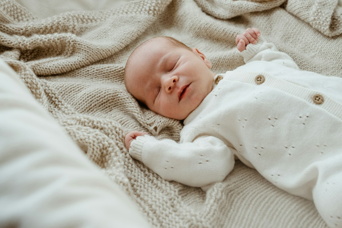 A newborn baby sleeps peacefully on a soft blanket