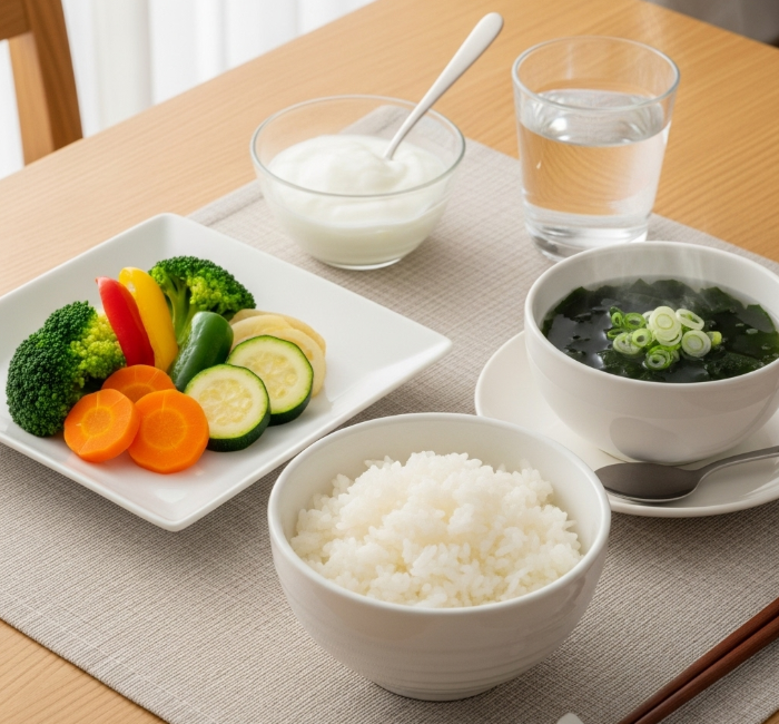 정갈한 식탁 위에 흰 쌀밥, 미역국, 순한 나물, 그리고 무설탕 요거트가 담긴 그릇이 놓여 있다. 장염 안정기에 적합한 건강하고 균형 잡힌 식단이다