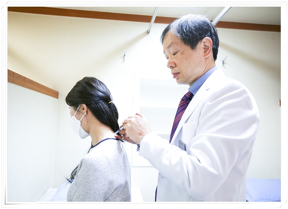 환자의 목 뒤에 약침을 놓고 있는 한의사의 모습