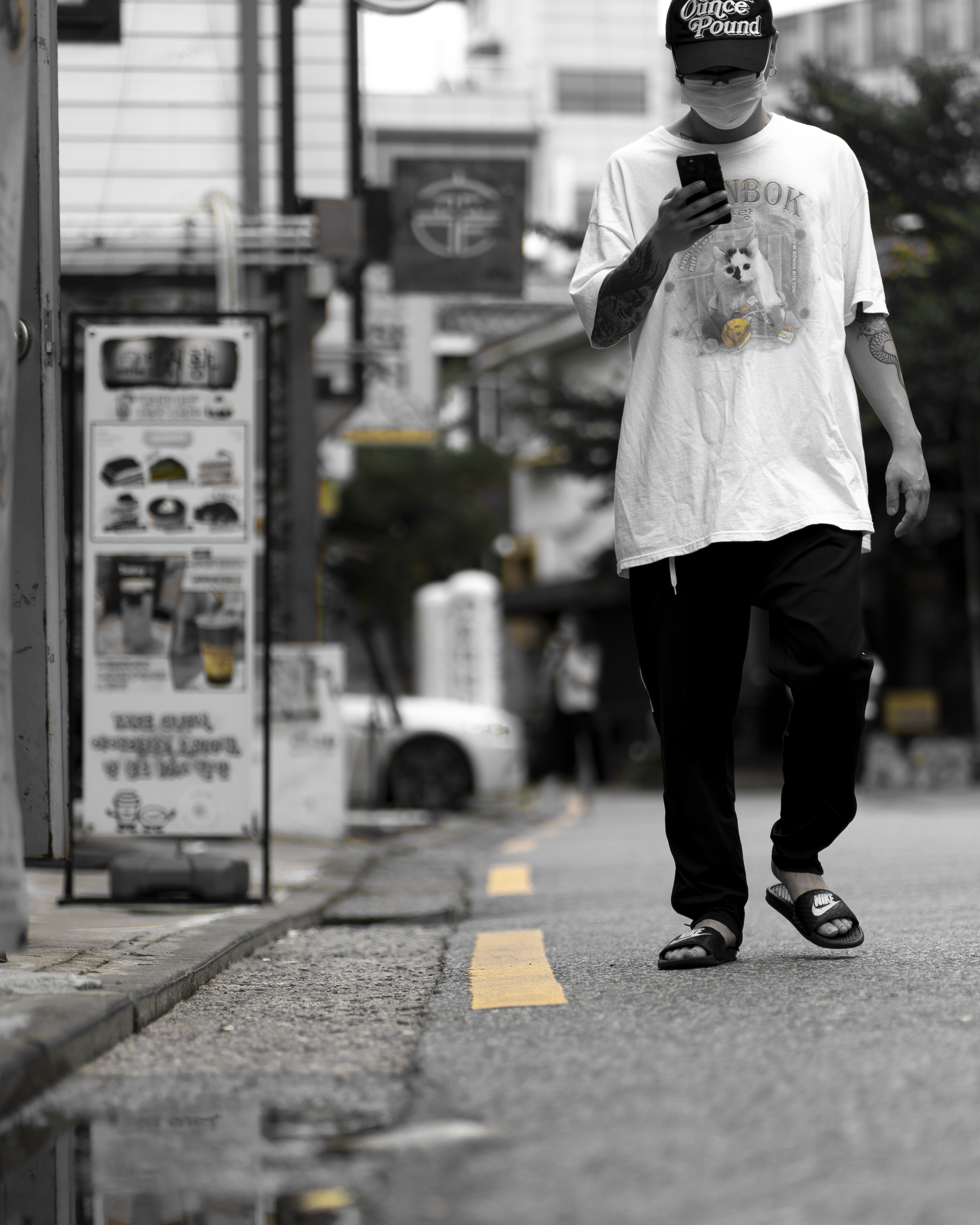 감성적인 흑백 사진. 노란색만 포인트로 살렸고, 지나가는 행인이 스마트폰을 보며 걷고 있다.