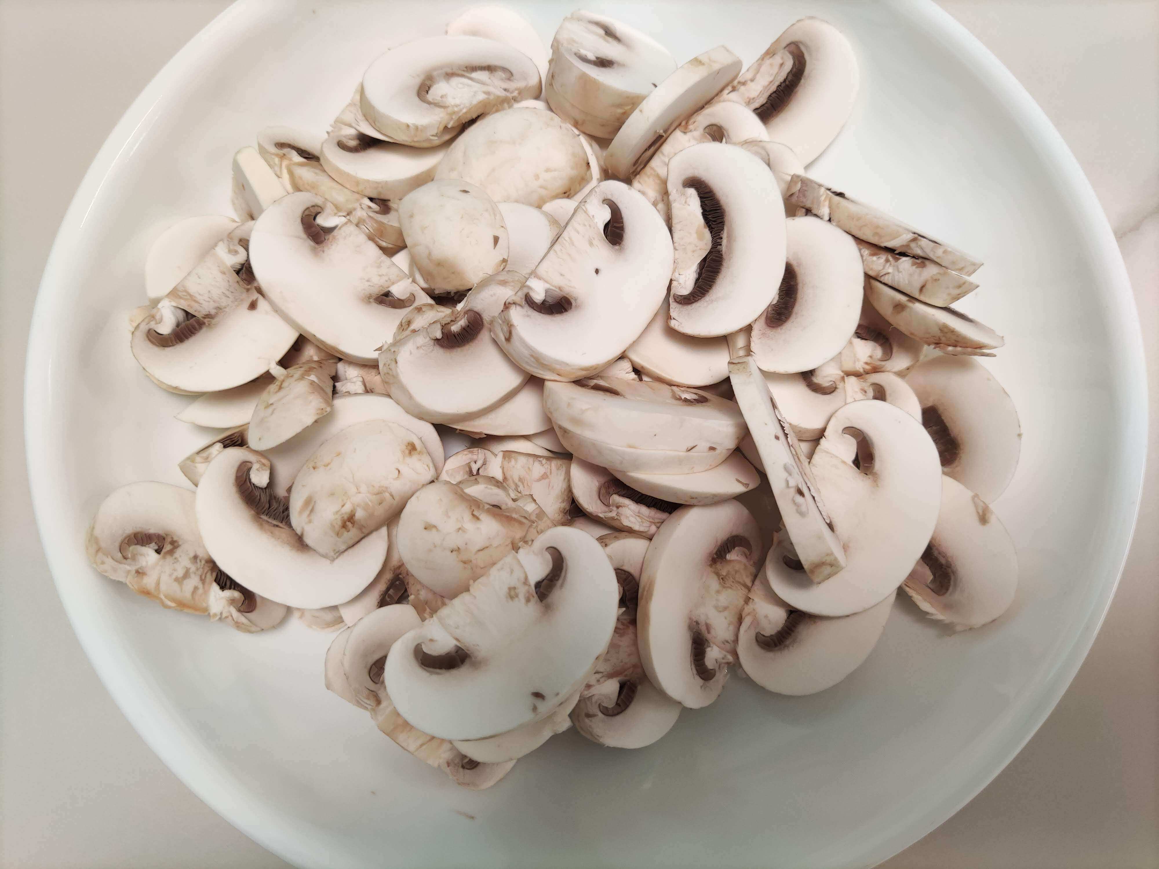 슬라이스 된 양송이버섯을 담은 흰 접시