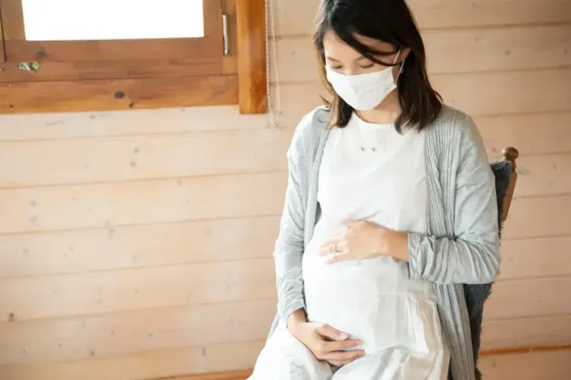 마스크를 쓴 임산부가 베이비페어 현장에서 부스를 관람하는 모습을 담은 이미지입니다.