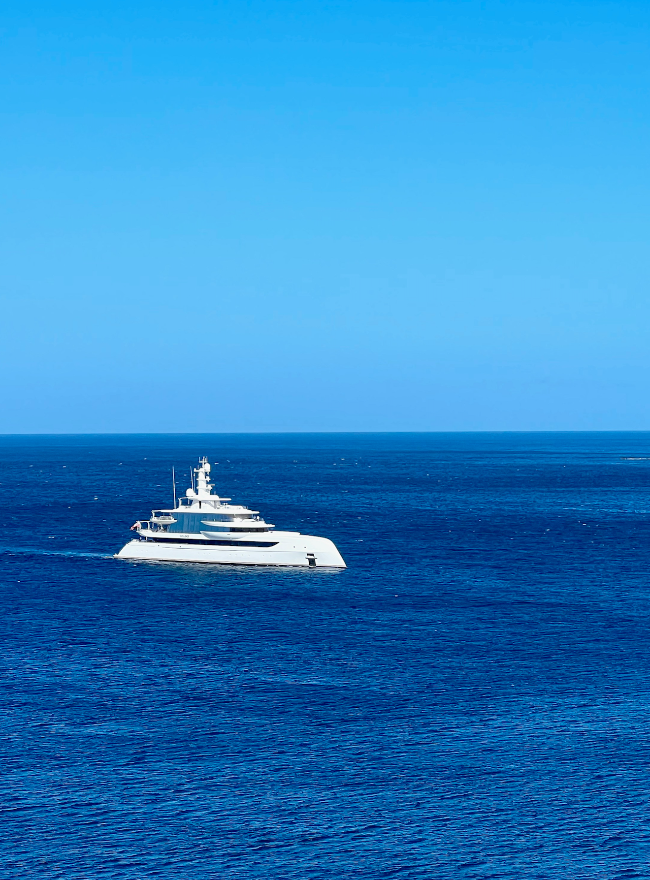 The sharp silhouette of a private superyacht carving its own path on the deep blue