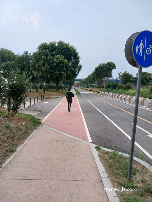 강변 도로 옆 보행자 전용길에서 슬로우 조깅을 하는 모습
