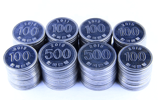 100원 동전들과 500원 동전들이 높이 쌓여있다. 앞줄엔 100워느 500원, 500원, 100원 동전줄이 있고, 뒷줄엔 100원 동전이 4줄씩 있다.