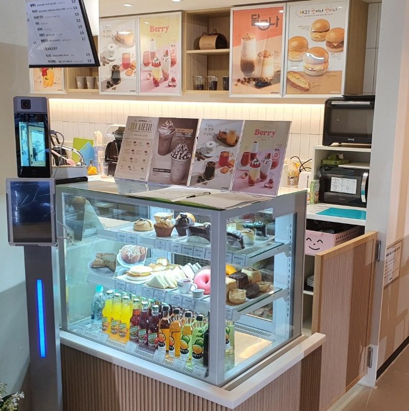 계산대 옆에 배치된 소형 메뉴판과 실물 디저트 쇼케이스 사진