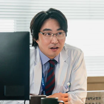 의사 가운을 입고 진료실 책상에 앉아 있는 드라마 열녀박씨 계약결혼뎐의 최현욱 캐릭터
