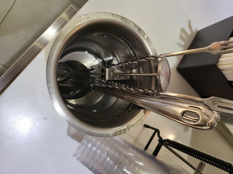 위생적으로 관리되고 있는 카페의 스푼 전용 물 피처 내부 모습. 맑고 깨끗한 물 안에 바 스푼과 온도계 등이 담겨 있으며, 이물질이나 탁함이 전혀 없는 정갈한 상태를 상징함.