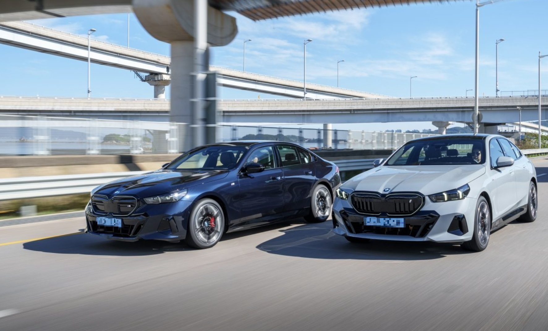 A sleek dark blue German sports sedan aggressively driving on a winding mountain road in the Bavarian Alps.