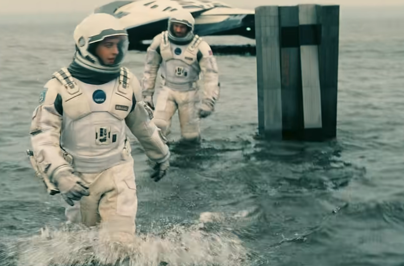 Two astronauts in spacesuits arriving on an alien planet get off the airship and walk on the ocean.