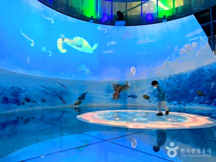 대형 스크린 앞에 어린아이가 구경하고 있다.