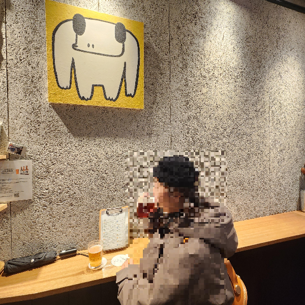 벽면 노란 액자가 눈에 띈다. 서서 맥주를 마시는 사람