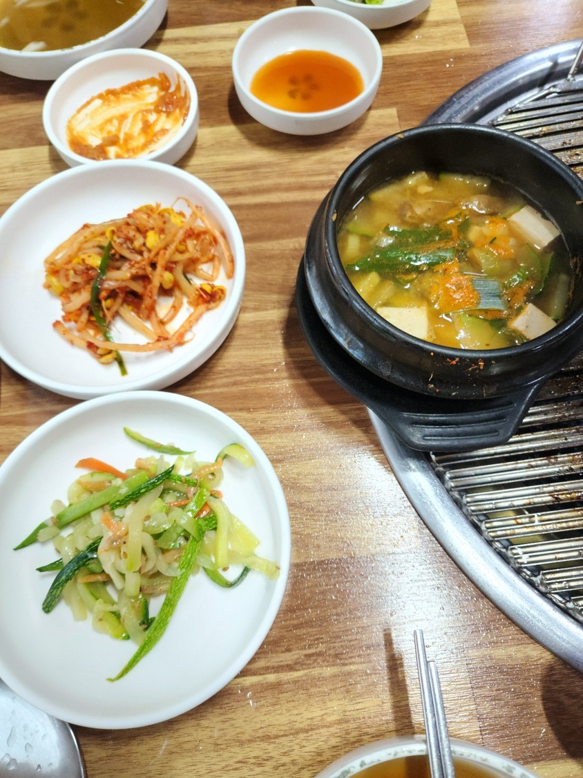 된장찌개와 반찬이 담긴 접시 3개가 테이블 위에 있다
