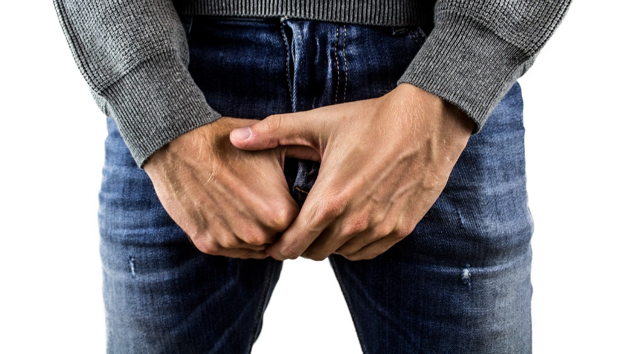 전립선 부위를 두 손으로 감싸고 있는 남자
