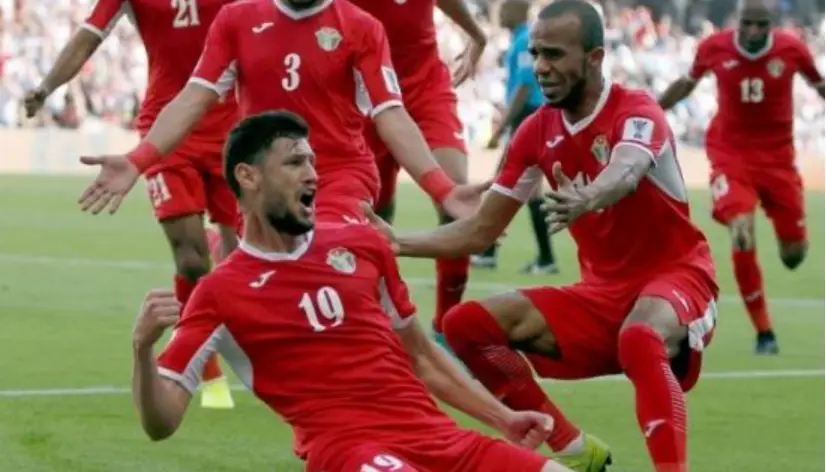 호주전- 붉은 유니폼을 입은 호주선수 한명이 축구장에서 미끄러지는 세레머니를 하고 있고 그 주변으로 축하하러 오는 선수들