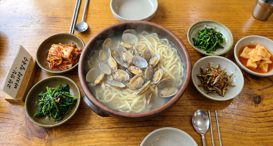 살이 꽉 찬 바지락 칼국수와 먹음직스러운 밑반찬이 차려진 한 상
